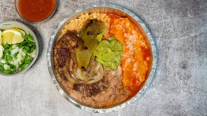 Carne asada plate with a cheese enchilada, guacamole, grilled onions and a chile, rice and beans